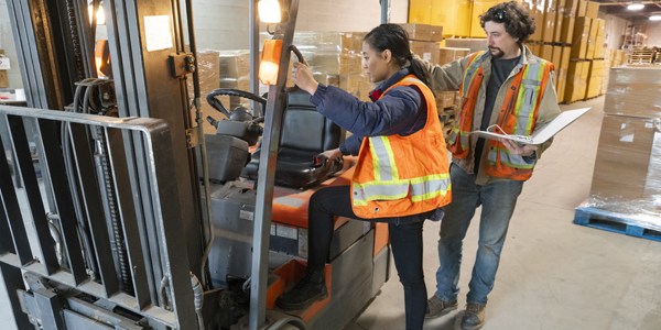 A safety supervisor training a new employee on forklift safety