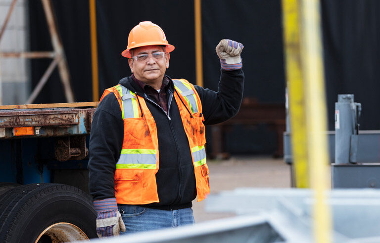 Hispanic worker wearing a hard hat and orange vest