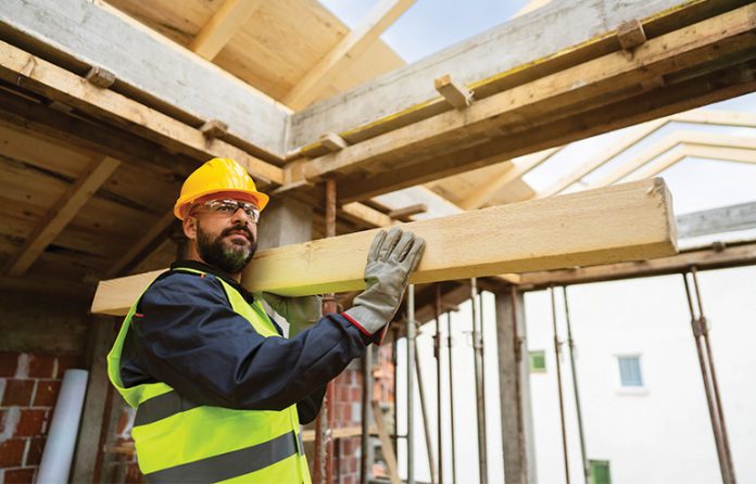 a construction worker carrying a piece of wood