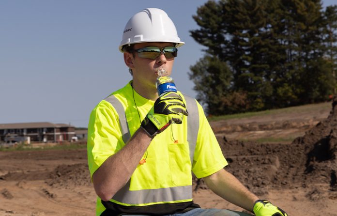 A male worker drinking water in the sun.