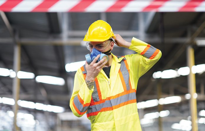 A male worker wearing a protective respirator mask